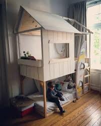 Barnrum med en tvåvånings lekstuga; säng nertill och lekyta ovanpå, framför ett fönster.
