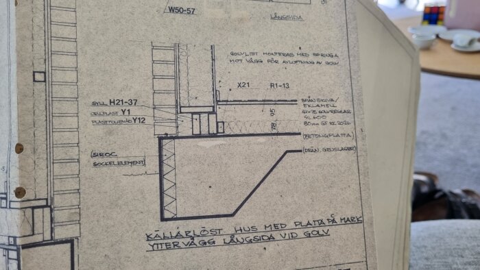 Detaljerad byggritning av grundkonstruktionen för ett hus, inklusive mått och materialinformation.