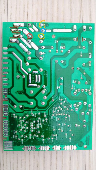 Kretskort baksida med komponentlödningar, vissa områden markerade för felsökning av relän.