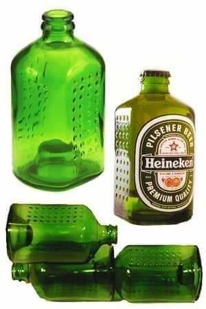Gröna glasflaskor skurna och omvandlade till dricksglas, bredvid en hel Heineken ölflaska.