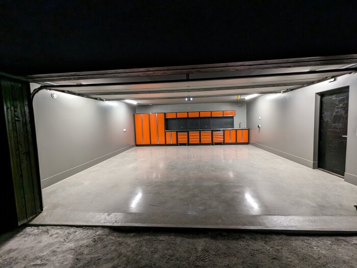 Renoverat garage med uppfälld port, polerat betonggolv och orange svart verktygsskåp.