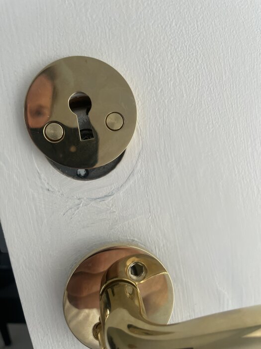 Nyckelbricka och handtag på en dörr, där brickan inte kan roteras och handtaget inte vrids uppåt.