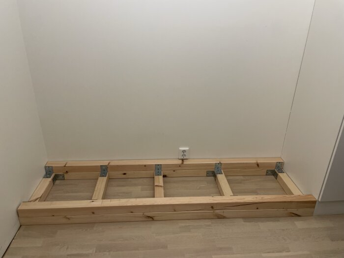 Grundram av trä som förberedelse för en MDF garderobsvägg, med väggfästen, i ett rum med lutande tak.