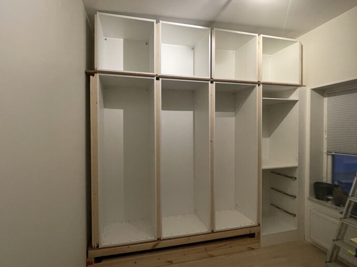 Obyggd MDF-garderobsvägg med Ikea stommar och anpassning till ett snett tak i ett rum under konstruktion.