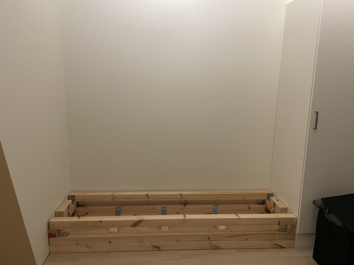 Påbörjat bygge av en garderobsvägg med Ikea-stommar och MDF-skivor mot ett snett tak.