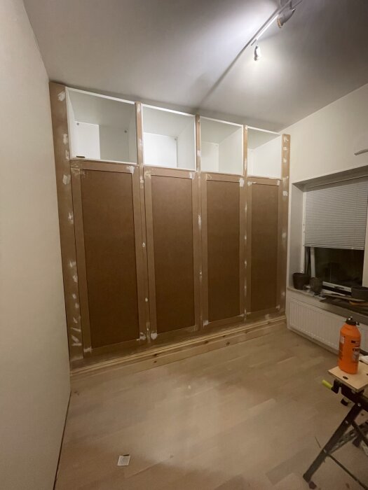 Under konstruktion av MDF garderobsvägg med vita Ikea stommar längs ett snedtak i rum.