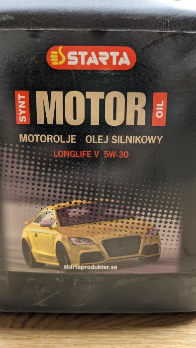 Flaska med motorolja märkt "STARTA MOTOR OIL SYNT Longlife V 5W-30" på träbänk.