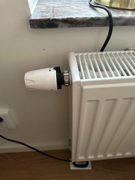 Termostat inställd på högsta nivå på en radiator, fast vid märkningen "TA