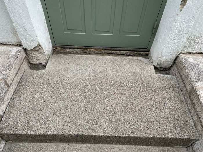 Återmonterad stentrappa med 10 cm glapp mellan fasad och steg utanför en dörr.