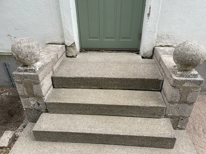 Återmonterad trappa med synligt 10 cm glapp mellan stegen och husfasaden, stenbalustrader på varje sida.