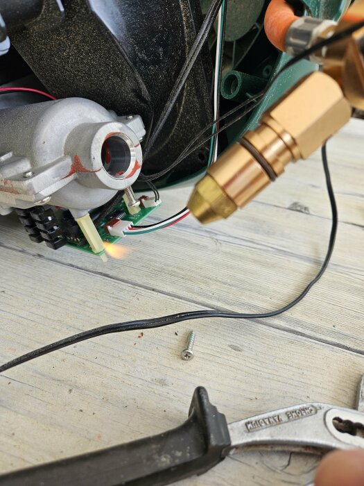 Närbild på myggfångstmaskinens insida med synlig låga vid tändningsområdet under reparation.