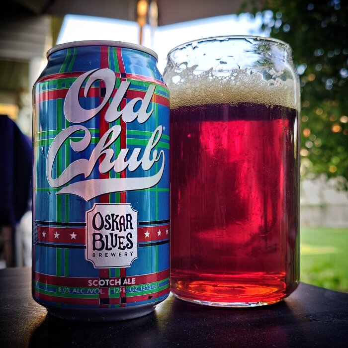 Burk av "Old Chub" skotsk ale från Oskar Blues Brewery bredvid ett glas fylld med rödbrun öl.