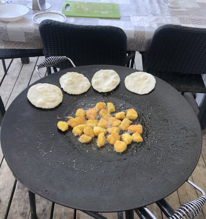 Fisktacos med tjocka bröd och panerade fiskbitar på ett svart bord utomhus.