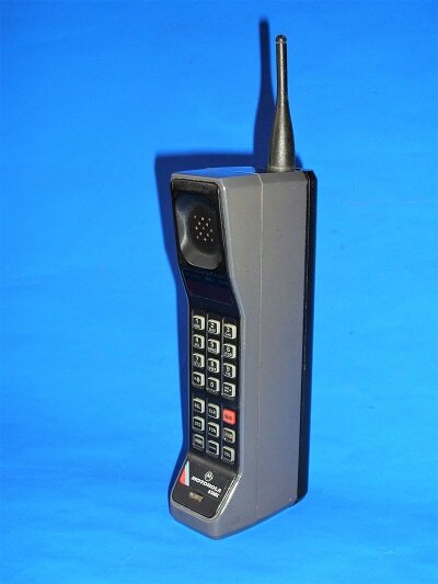 Vintage grå Motorola 4500X mobiltelefon känd som tegelstenstelefon från 1988 mot blå bakgrund.