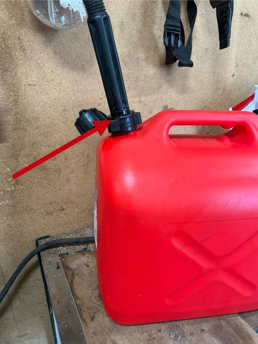 Röd bensindunk med påfyllningsrör markerat där det läcker vid anslutningen.