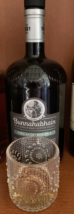 Flaska Bunnahabhain Islay Single Malt Scotch Whisky bakom tomt whiskyglas.