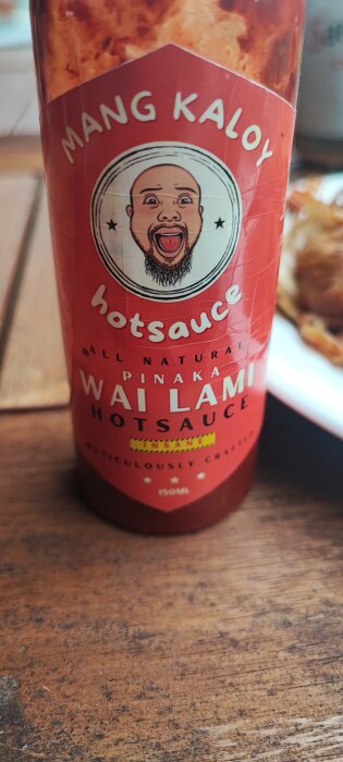 Flaska med "Mang Kaloy" hotsauce och tecknad person på etiketten, med texten "insane" framhävd.