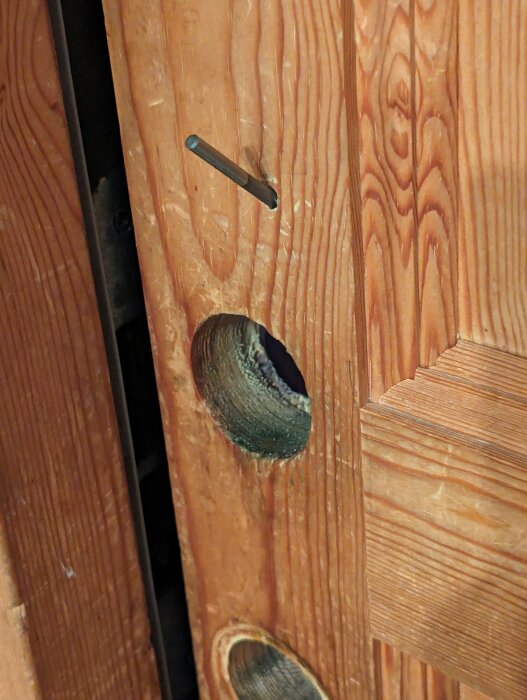 Närgräns av en öppen ytterdörr med synlig låskolv och urtagen låskista, före smart låsmodifiering.
