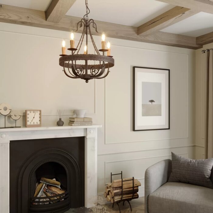 Rustik ljuskrona med fem ljuskällor upphängd i ett vardagsrum med öppen spis och en grå soffa.