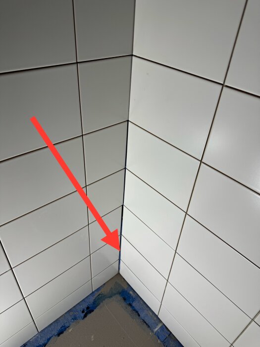 Hörnet i ett kaklat duschutrymme där tätskiktsfolien inte ligger an mot väggen och behöver en bred silikonfog.