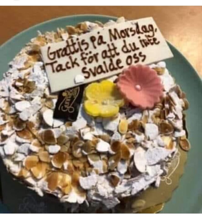 Tårta dekorerad med nötter och en chokladplakett som säger "Grattis på Morsdag, tack för att du inte svalde oss".