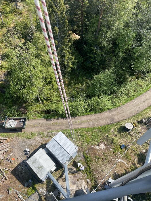 Vy från ovan på radiolänkutrustning och skogsmark med del av arbetsfordon och rep.