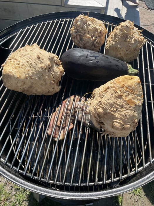 Rökt vildsvinstek och grönsaker med rotselleri och en aubergine på en grill.