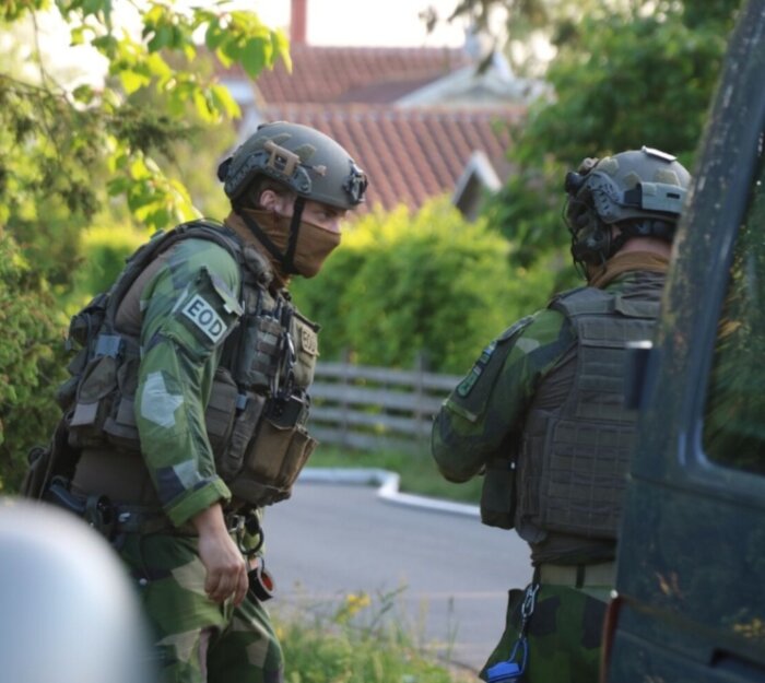 Två poliser i full skyddsutrustning samtalar utomhus.