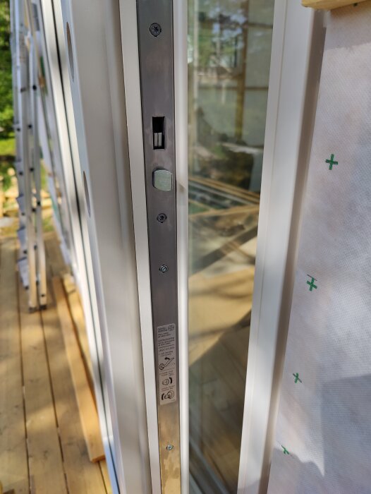 Detaljbild av en vit dörrens kant med lås, lift-to-lock-funktion, och dörrstängningsmekanism.