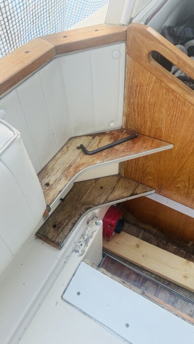 Delar av en båtinredning under renovering med träskåp, en demonterad trappa och verktyg på golvet.