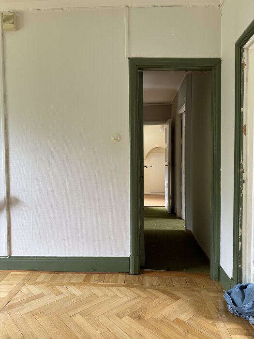 Gammalt hus interiör med lutande golv synligt i en passage, och en sågad dörrpost anpassad för golvets vinkel.