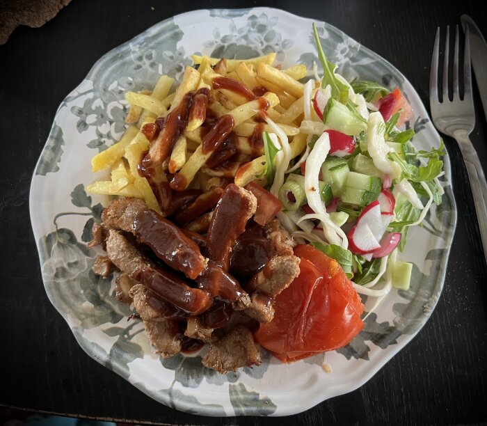 Tallrik med ryggbiff, pommes, ugnsgrillad tomat, sallad och rödvinssås.