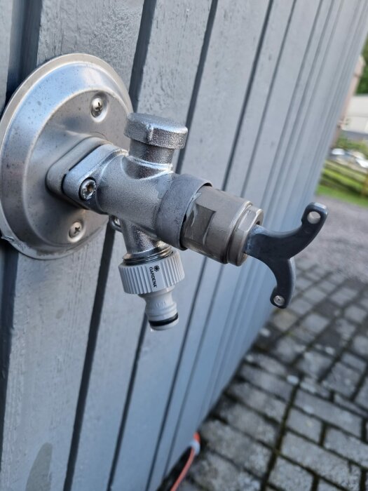 Väggmonterad vattenutkastare med läckage vid nyckeln, monterad på grå vägg.