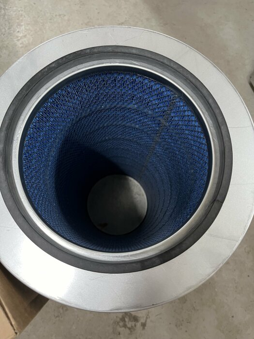 Översikt av en blå patronfilter med silverfärgad topp sett uppifrån som används i ett dammfiltreringssystem.