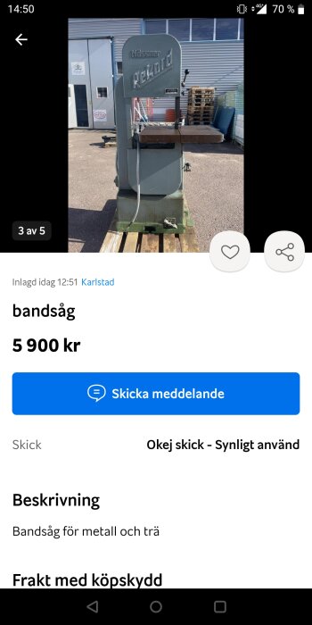 Bandsåg för metall och trä utsatt till försäljning utomhus mot en byggnad och pallar.