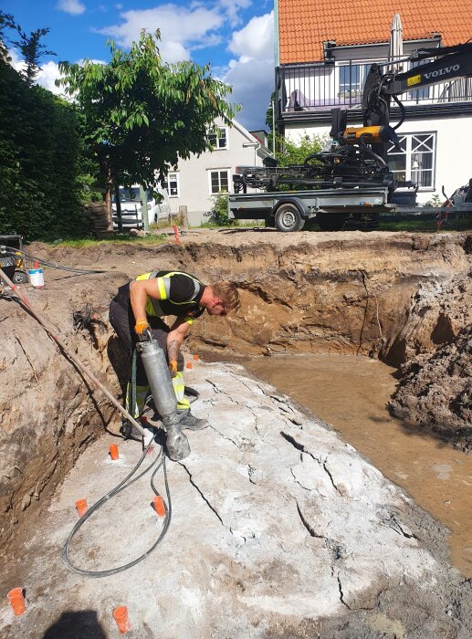 Arbetare förbereder bergspräckning nära grävmaskin på byggplats.