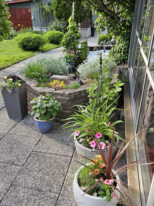 Grönskande trädgård med krukor och amplar fyllda med växter vid en damm.