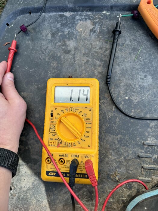 En multimeter som visar en mätning på 1,14 på en elektrisk anslutning testerad utomhus.