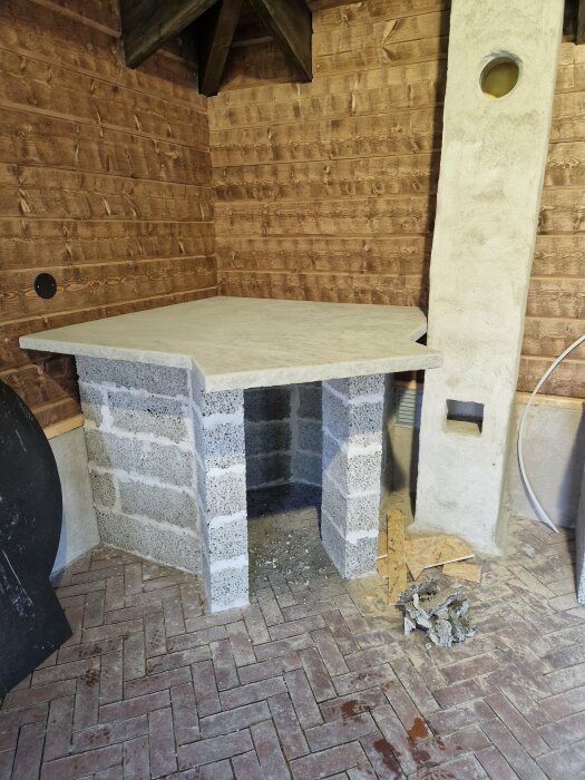 Hemmagjord arbetsbänk av lättbetongblock och rektangulär bordsskiva i en hörna av ett träskjul.