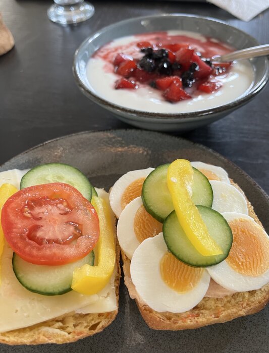Frukost med fil och bär samt smörgåsar med ost, grönsaker och ägg.