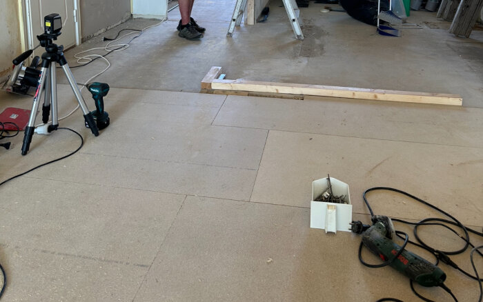 Renoveringsarbete av golv med verktyg och material synliga på golvspånskivor.