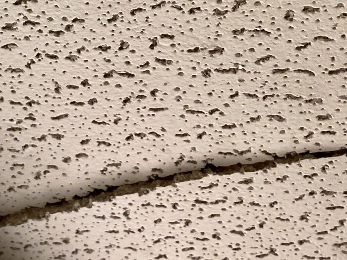 Närbild av en bitad undertaksplatta med porös struktur som kan innehålla asbest.