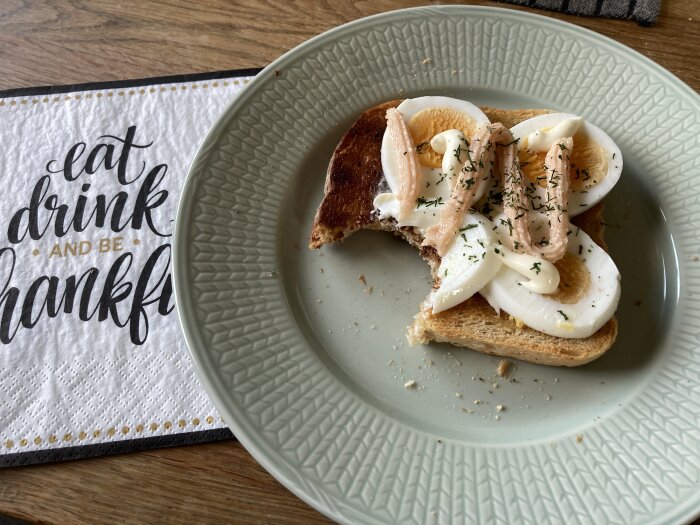 Äggmacka med skivat ägg och kryddor på en talrik, delvis uppäten, på ett köksbord.