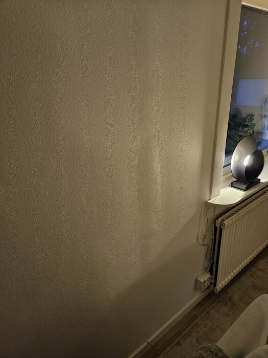 Vertikala bucklor på inomhusvägg ovanför en radiator i ett vardagsrum.