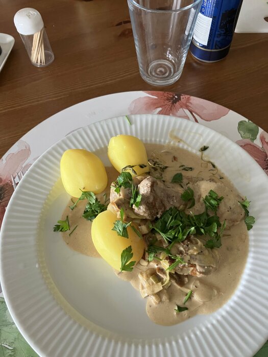 Höstgryta med fläskfilé, svamp och purjolök, serverad med kokt potatis och garnerad med persilja på tallrik.