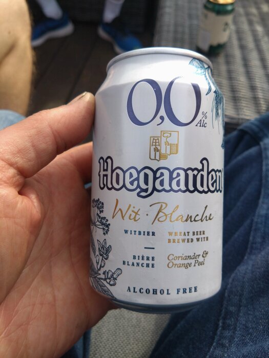 Hand håller en burk Hoegaarden alkoholfri öl ombord på en bastubåt.