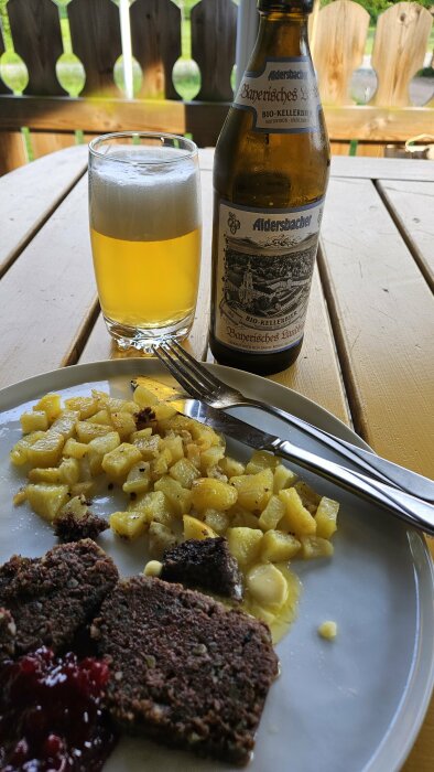 Middag på altan med stekt lever, potatis, lingon och en öppnad flaska Kellerbier Aldersbacher på ett bord.