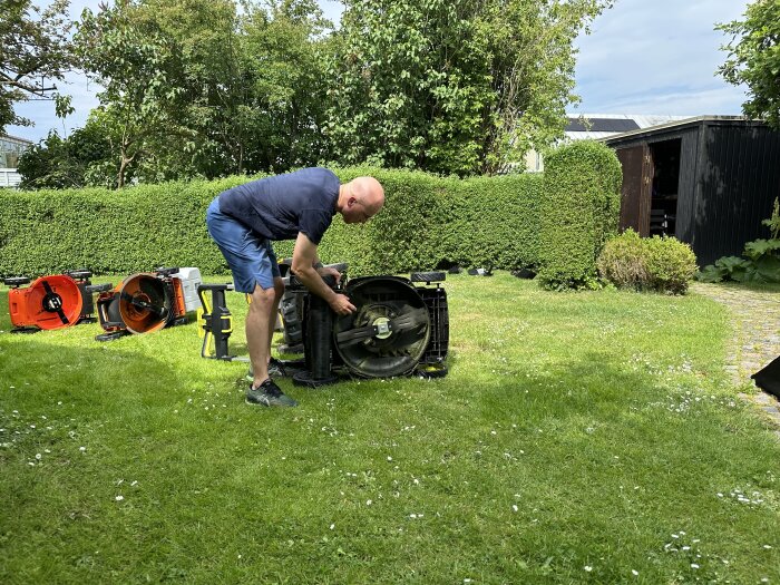 Man testar en uppochnervänd gräsklippare på en gräsmatta med flera gräsklippare i bakgrunden.