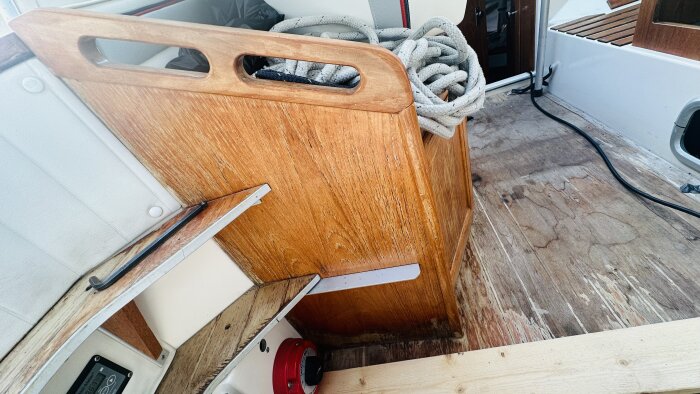 Del av en motorbåts inredning under renovering visandes träytor och sittbrunnens slitna golv.