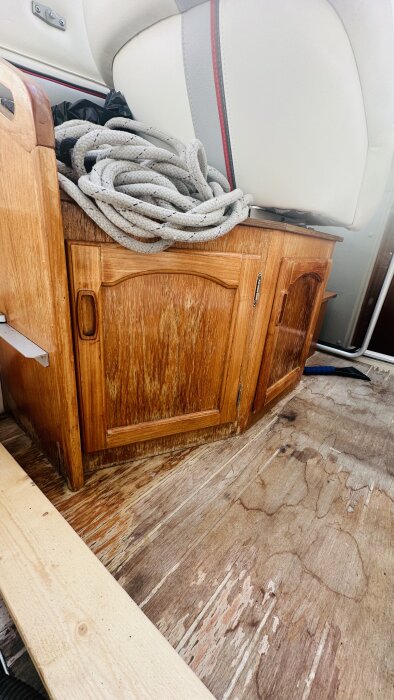 Slitet träskåp och däck i en båt med behov av renovering, tillhörande ett båtprojekt.